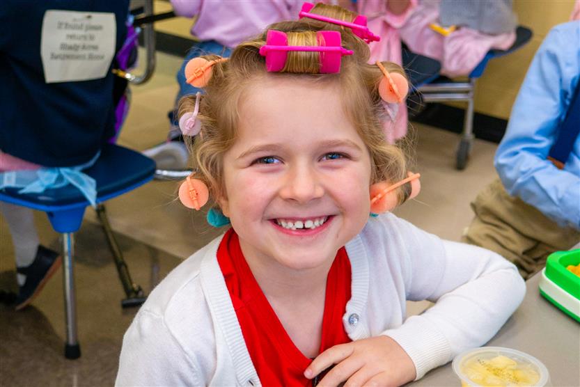girl smiling with curlers in her hair